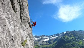 Ausgesetzte Wandstelle mit tollem Bergpanorama (Fürenwand Klettersteig).